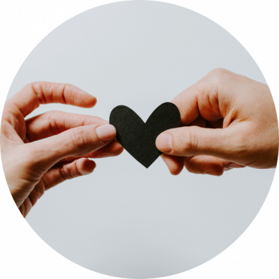 An image of two hands holding a black paper heart