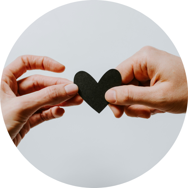An image of two hands holding a black paper heart